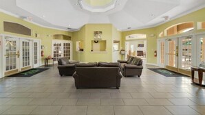 Eine geräumige Lobby mit hoher Decke, mehreren Sitzbereichen und einem zentralen Kamin.