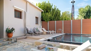 A pool area with lounge chairs, a stone patio, and a white building with windows.