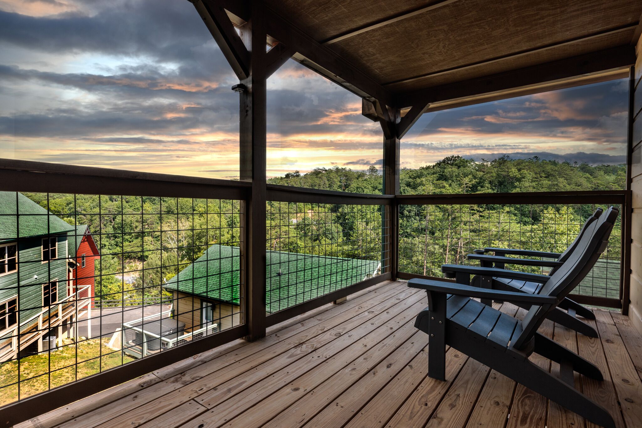 Eine Holzterrasse mit Blick auf eine grüne Landschaft und ein rotes Gebäude.