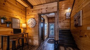 Un intérieur en bois avec un escalier en bois, une horloge, une statue d’ours et une pancarte portant une citation.