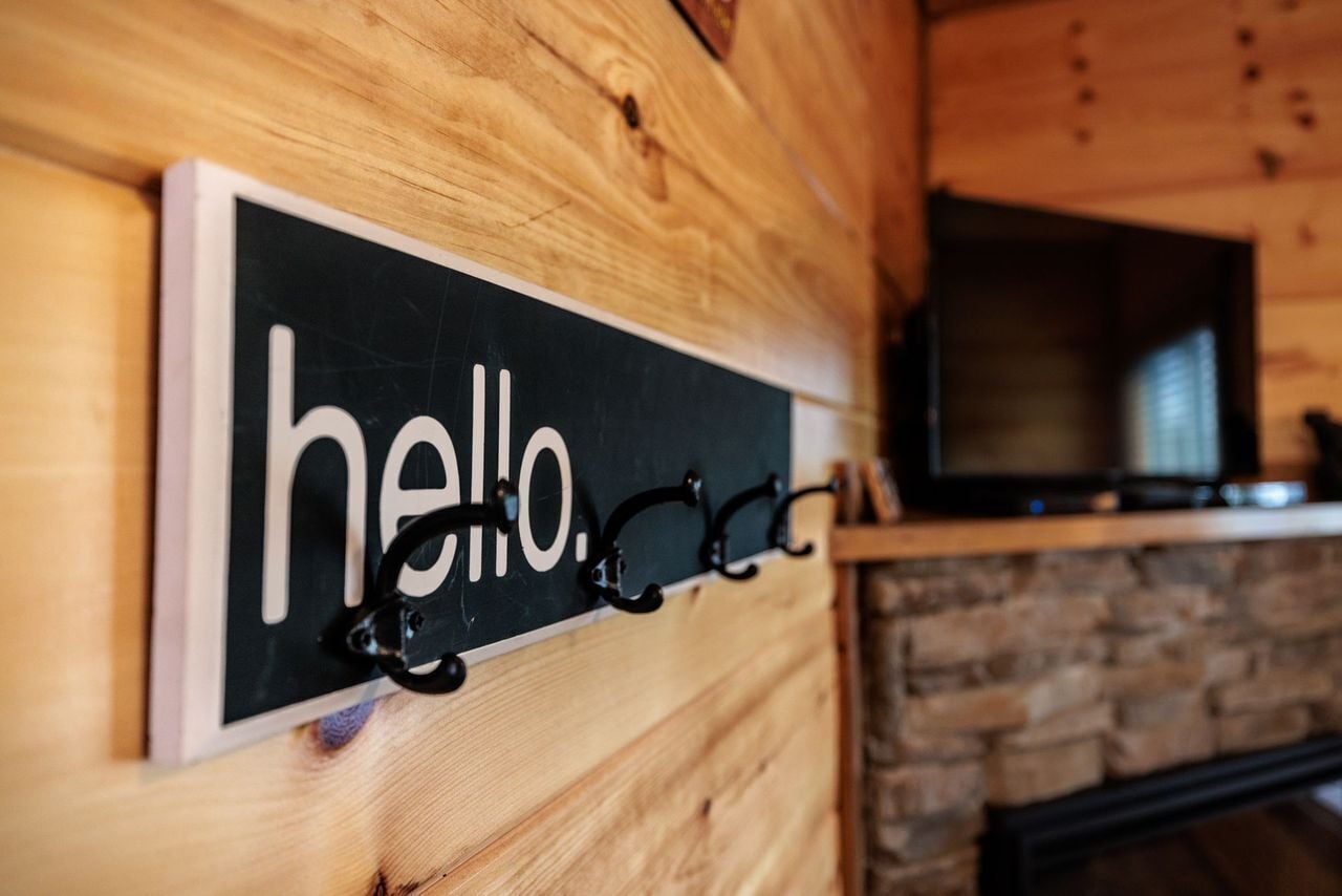 A wooden wall with a black sign reading "hello." and a television mounted above it.