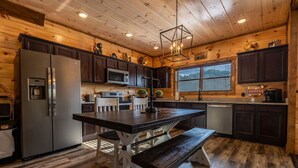 Une cuisine moderne avec des meubles en bois foncé, des appareils électroménagers en acier inoxydable et un îlot central doté d’un banc.