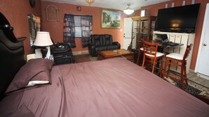 Habitación de hotel con cama, escritorio con computadora, silla, sofá, lámpara y televisión.