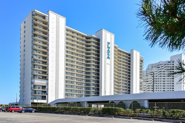 A high-rise hotel with multiple balconies, a prominent 'Palo Alto' sign, and a parking area in front.