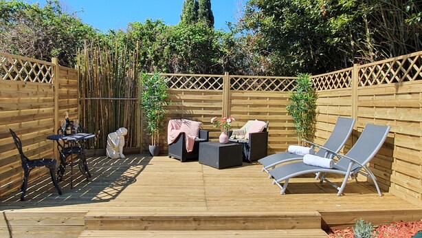 A wooden deck with outdoor furniture, including chairs and a table, surrounded by a wooden fence. - Hideaway gite for 2 with private garden and sundeck, close to Atlantic beaches. (Épargnes)