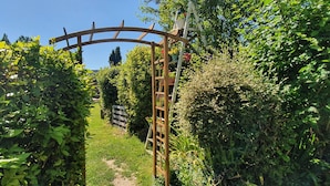 A garden pathway with a wooden archway and a ladder. - Hideaway gite for 2 with private garden and sundeck, close to Atlantic beaches. (Épargnes)
