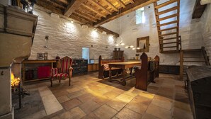 Una camera rustica con camino in pietra, arredi in legno e una zona soppalco accessibile tramite una scala in legno.