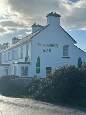 Un edificio blanco con el letrero 'MINIHAN'S BAR' en su fachada.