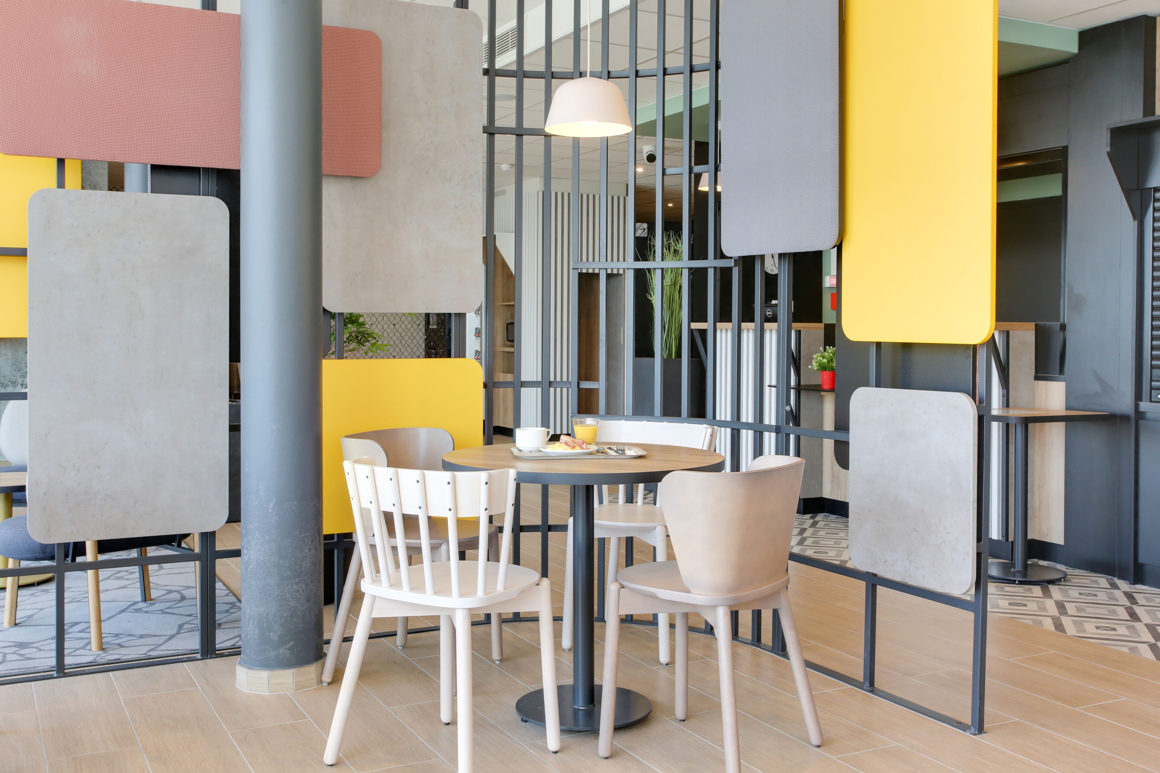 A modern cafe with round tables and white chairs, featuring a yellow and gray color scheme.