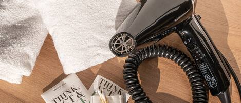 A hair dryer, a white towel, and two pamphlets on a wooden surface.