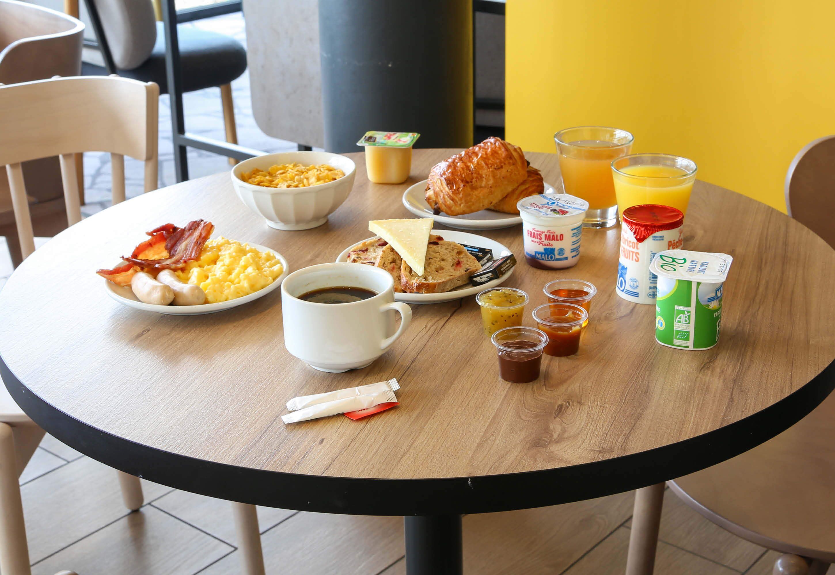 A breakfast table with various food items, including eggs, bacon, toast, and juice.