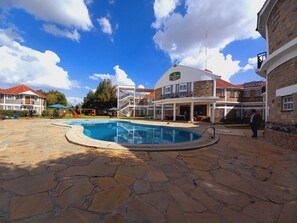 A swimming pool area with stone flooring, a children's play area, and a building labeled "Athli Holiday Resort".