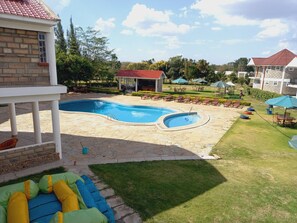 A swimming pool with a stone deck, lounge chairs, and a covered pavilion. - Athi Holiday Resort (Athi River)