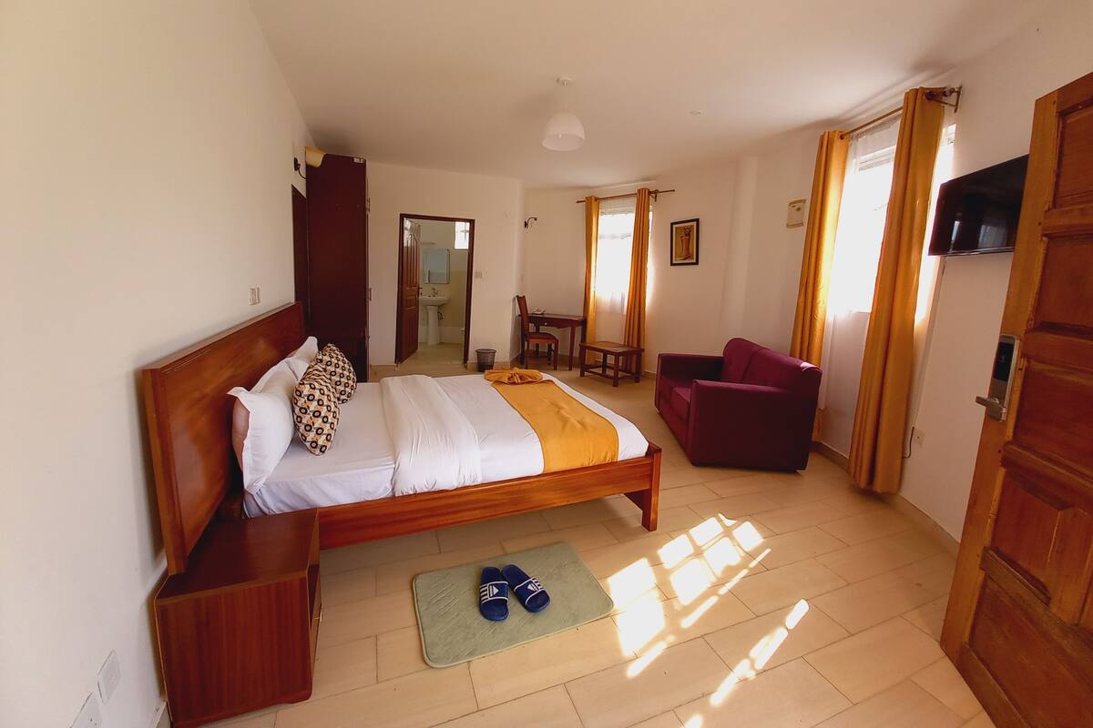 Ein Schlafzimmer mit einem Bett, einem Sessel, einem Schreibtisch und einem Fernseher.