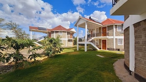 A two-story house with a red-tiled roof, a covered patio, and a small garden. - Athi Holiday Resort (Athi River)