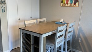 Comedor con mesa y sillas de madera, una lámpara colgante y un adorno en la pared.