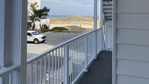 Balcón cubierto con vista a un estacionamiento y una playa.