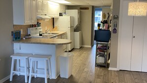 Una cocina moderna con armarios blancos, una isla central con taburetes, un refrigerador y un microondas.