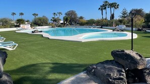 Une piscine entourée d’une pelouse et dotée de chaises longues.