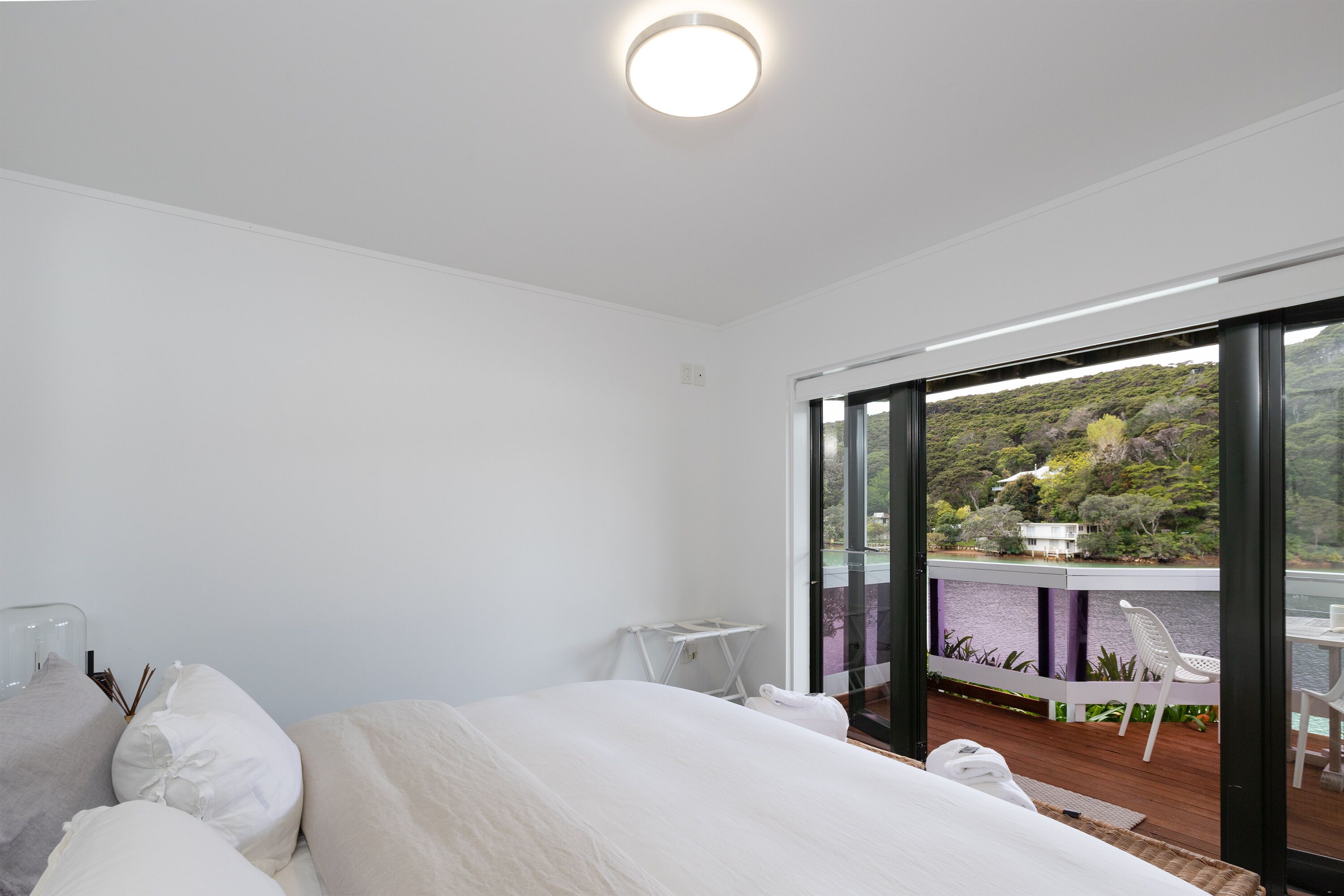 Une chambre avec un grand lit, une petite table et une vue sur un balcon aménagé avec du mobilier d’extérieur.