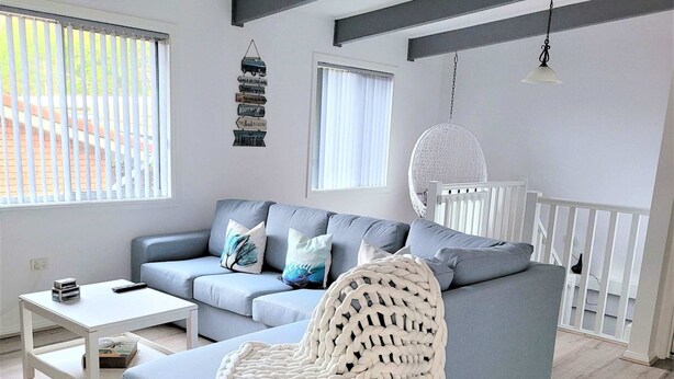 A modern living room with a grey sofa, white coffee table, and a white woven chair. - Beachside Escape, WiFi & Pet-Friendly | Riptide (Lilli Pilli)