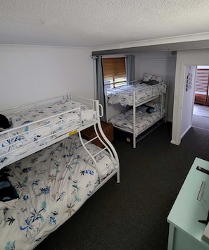 A room with bunk beds, a desk, and a window with blinds.