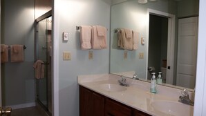 Un baño con dos lavamanos, un espejo grande y una cabina de ducha de vidrio.