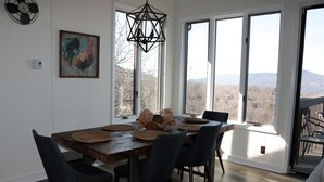 Ein Essbereich mit einem Holztisch, schwarzen Stühlen, gewebten Platzsets und einem Wandbild mit einem Hahn.