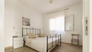 Una camera da letto con un letto, un comodino e una sedia.