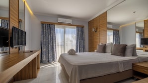 A modern hotel room with a large bed, a TV, and a wooden desk. - Ladonia Hotels Mio Bianco  (Bodrum)