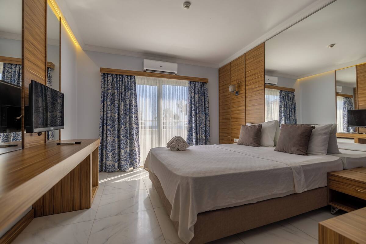 Una habitació d'hotel moderna amb un llit gran, una televisió i un escriptori de fusta.