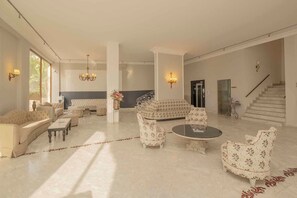 Un vestíbulo espacioso con techo alto, una escalera imponente y una sala de estar con sofás y sillones.