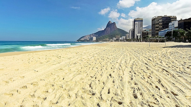 A wide sandy beach with footprints, a clear blue sky, and a mountain in the background. - Rio Spot Leblon D049 (Rio de Janeiro)