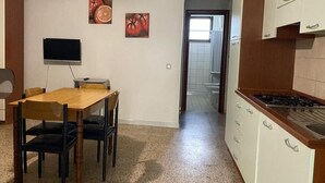 A kitchen with a dining table, chairs, a TV, and a stove.