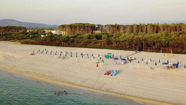 A beach with umbrellas and lounge chairs.