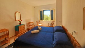Een slaapkamer met een bed, een kapstok, een stoel en een raam.