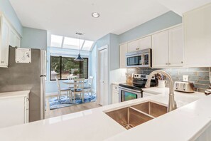 A modern kitchen with white cabinetry, a stainless steel microwave, and a built-in oven.