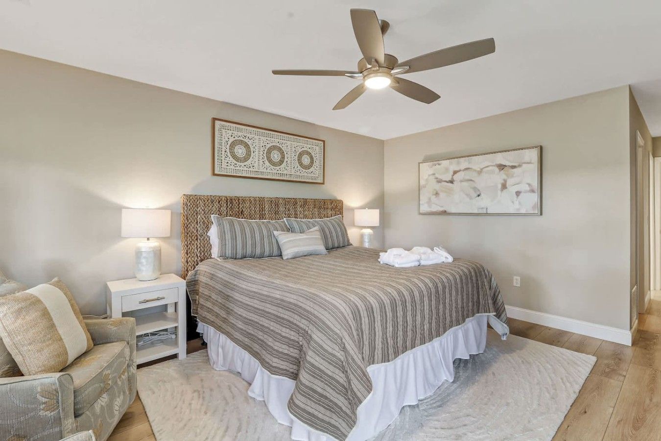 A bedroom with a bed, nightstands, a ceiling fan, and artwork on the walls.