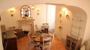 A dining area with a round table, chairs, a fireplace, and wall-mounted sconces.