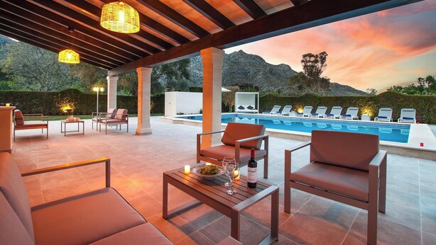 Un espace extérieur aménagé avec une piscine, des chaises longues et une table sur laquelle se trouvent une bouteille et des verres.