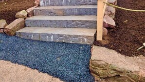 Un escalier en bois, avec des marches en pierre, menant à une maison.