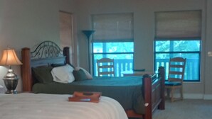 A bedroom with a large bed, a nightstand, a lamp, a window with a view, and a ceiling fan. - The Lodge @ Stormy Mountain Ranch Close drive to Emience and surrounding springs (Birch Tree)