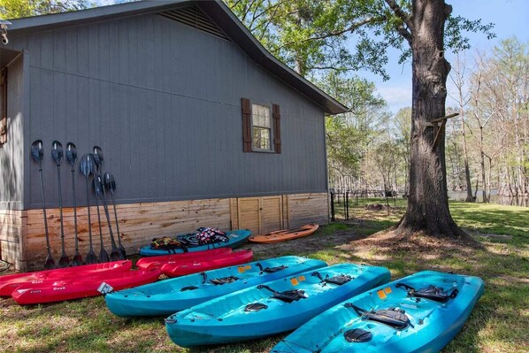 Un edificio con kayaks y palas guardadas afuera.