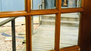 Ventana de madera con vistas a una terraza de madera y un edificio al fondo.