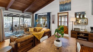 Una sala de estar acogedora con techo de madera, una mesa de comedor y un sofá.