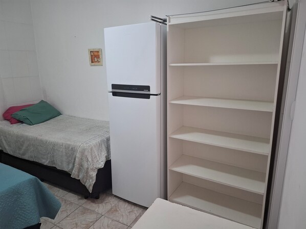 A bedroom with a bed, a wardrobe, and a small table. - Studio BeiraMar-Praia Grande, Aviação-Free 500MB WiFi  (Praia Grande)