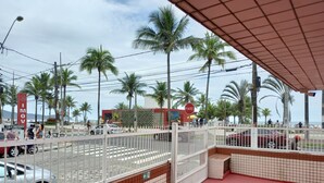 A beachside street with palm trees, a pedestrian crossing, and a building with a sign that reads "IMOV". - Studio BeiraMar-Praia Grande, Aviação-Free 500MB WiFi  (Praia Grande)