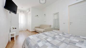 Une chambre à coucher comprenant un lit, une télévision, un canapé, une petite table et une armoire.