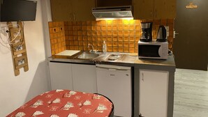 A compact kitchen with wooden cabinets, a microwave, a coffee maker, and a dishwasher.