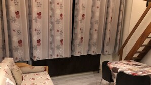 A cozy room with a sofa and a dining table with chairs.